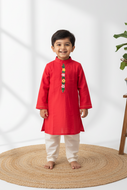 Child wearing a red kurta with white pants on a light background with embroidery done